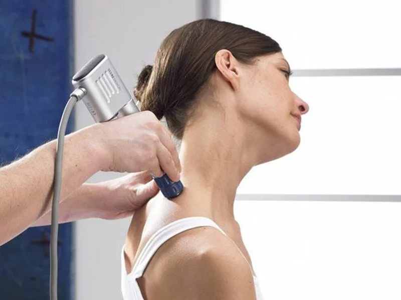 Doctor of Physical Therapy administering shockwave therapy on a patient's shoulder